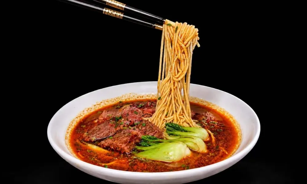 Spicy beef noodles with greens, chopsticks lifting noodles